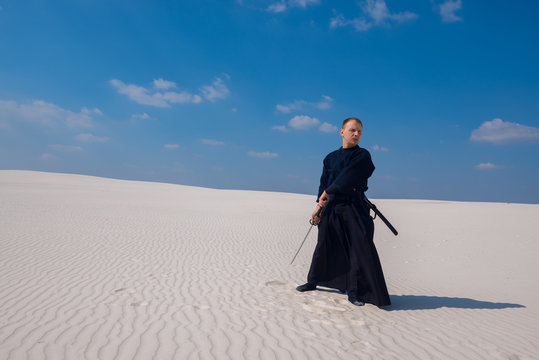 Confident man, with katana among sand dunes