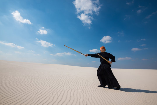 Caucasian man is practicing kendo in a desert