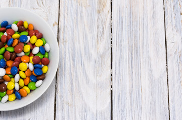 The plate is filled with sweets. Multicolored pellet. Copy space.