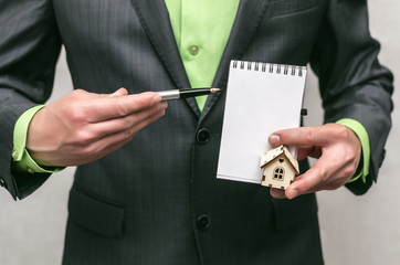 Real estate agent. Insurance agent. Realtor man holds in hands a toy house and documents.
