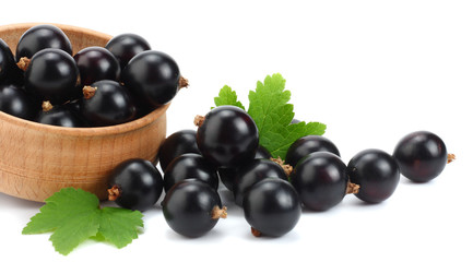 black currant in wooden bowl with green leaf isolated on white background