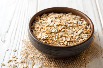Oat flakes in ceramic bowl on white wooden table