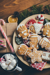 Plate with Christmas cookies on wooden table with cup of hot chocolate and gifts