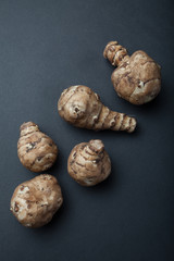 Strawberry Jerusalem artichoke or Jerusalem artichoke (Helianthus tuberosus) isolated on a black background, vertically.