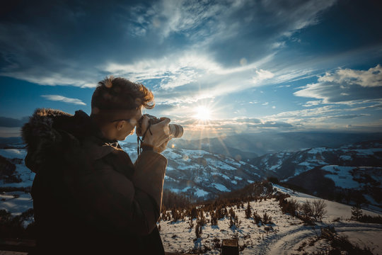 Photographer photographing sunset over beautiful winter landscape,back light