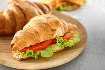 Plate with delicious croissant sandwich on table
