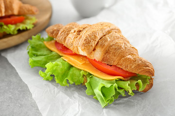 Delicious croissant sandwich on table
