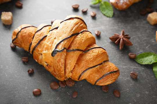 Delicious croissant with chocolate syrup on table