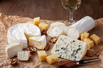 Variety of different cheese with wine, fruits and nuts. Camembert, goat cheese, roquefort, gorgonzolla, gauda