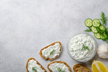 Homemade greek tzatziki sauce in a glass bowl with ingredients a