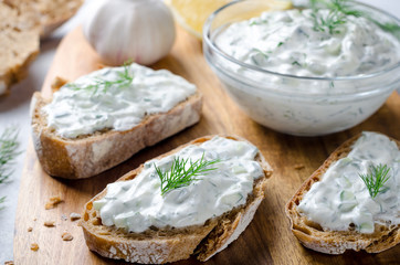 Homemade greek tzatziki sauce in a glass bowl with sliced bread