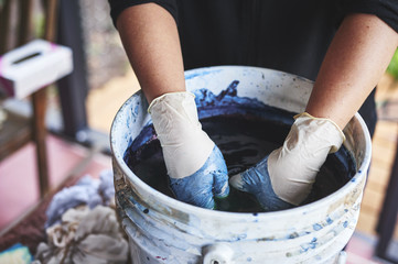 a woman soaking fabric in indigo dye.
