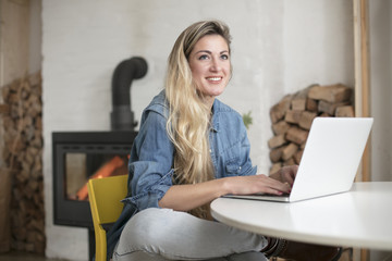 Young beautiful woman works for a computer from a home with a laptop on a white desk as a freelancer