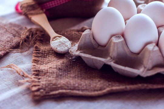 eggs and a spoon with flour on a sackcloth