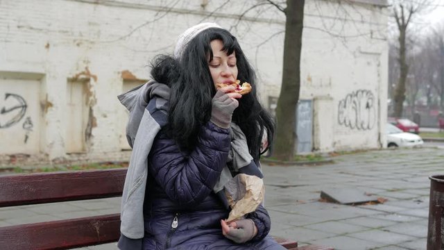 Hobo young woman eats meal at the street