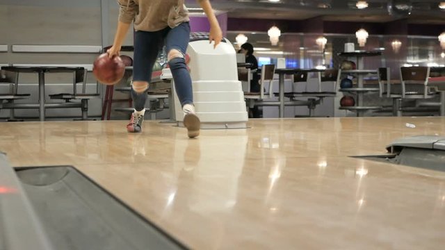 Woman in club for bowling is throwing ball.