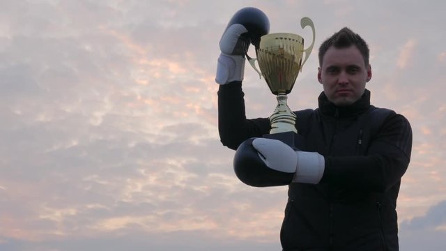 Strong man in a boxing gloves on the summer sky background