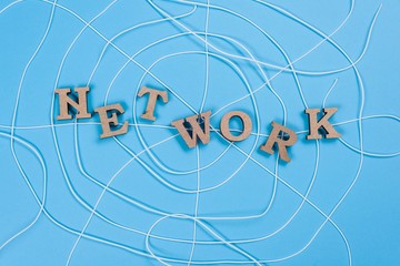The word network with wooden letters in the form of an abstract spider web, blue background.