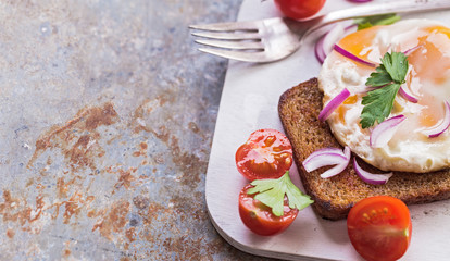 Sliced tomato and fried egg toast on old metal background with copy space 