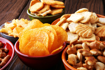 Salty snacks. Pretzels, chips, crackers on brown wooden background