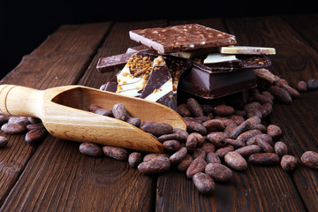 Dark chocolate pieces, stacks and cocoa beans, culinary background.