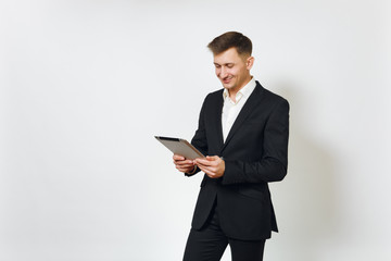 Young successful handsome rich business man in black suit working on modern tablet isolated on white background for advertising. Concept of money, achievement, career and wealth in 25-30 years.