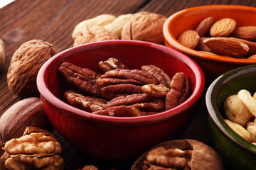 bowls with mixed nuts on wooden background. Healthy food and snack. Walnut, pecan, almonds, hazelnuts and cashews.