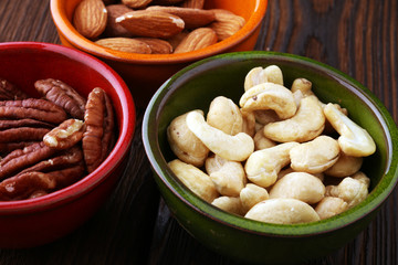 bowls with mixed nuts on wooden background. Healthy food and snack. Walnut, pecan, almonds, hazelnuts and cashews.