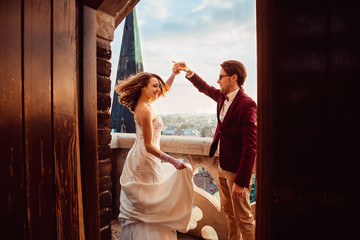 Newlyweds dance on the balcony of an old building from which a b