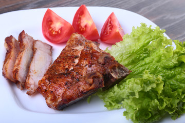 grilled pork chops with tomato, leaves lettuce and ketchup on plate.