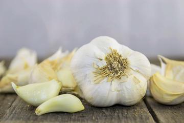 Garlic and parts in the shell and shelled on a rustic wooden surface with a white background