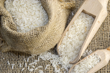 White rice in a rustic bag on a wooden surface 
