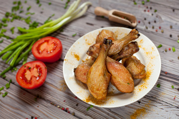 baked in the oven chicken legs with green onions and tomatoes on a wooden board on a light wooden background