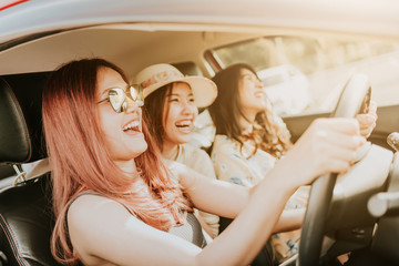 Group of happy Asian girl friends laughing and smiling in car during a road trip to vacation.