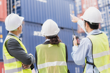 Back view of businessman with staff in logistic, export, import industry checking shipping cargo container freight.