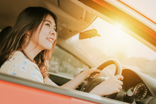 Confident And Smile Beautiful Asian Woman Driving A Car In Morning Sunlight