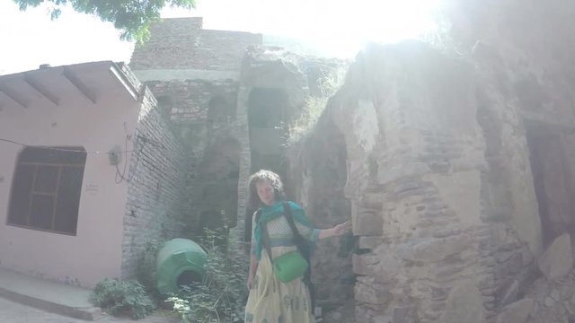 Caucasian woman walks through ancient ruins in India, curiously touching them, smooth tracking shot. 3X slow motion.