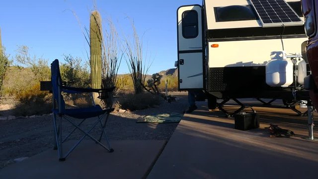 A man relaxes with a cup of coffee while camping in a recreational vehicle 