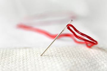 Needle in canvas with red thread for embroidery. Embroidery macro close up. View from above. Free copy space. - 184762850