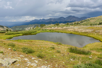 Fototapeta na wymiar Mountain Pond - Late summer view of a small tundra pond and surrounding high peak range at the summit of Cottonwood Pass (12,126 ft), Colorado, USA.