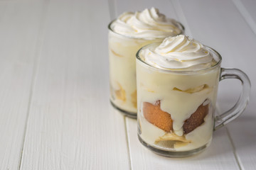 Banana dessert with whipped cream and biscuit on a rustic table.