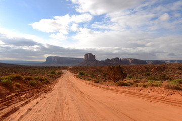 Desert Valley Road - A unpaved red sandy road extending into a desert valley at far. Monument Valley, Utah & Arizona, USA.