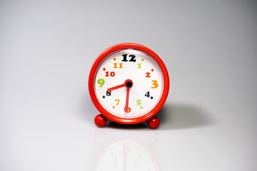 Red alarm clock with time shows 8.30 o'clock with reflections on isolated white background.