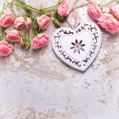 Border from  pink roses flowers and decorative heart on grey vintage textured background.