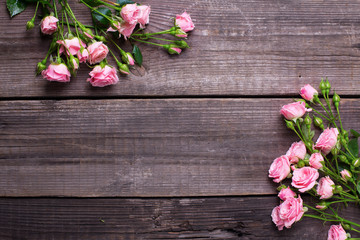 Fototapeta na wymiar Border from tender pink roses flowers on vintage wooden background. Floral still life.