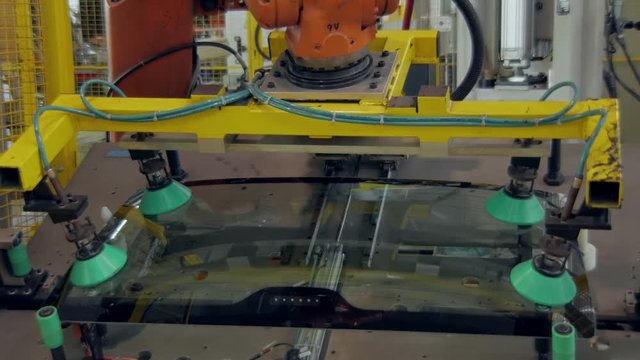 robot is gripping a back car windows and lifting up in a car factory