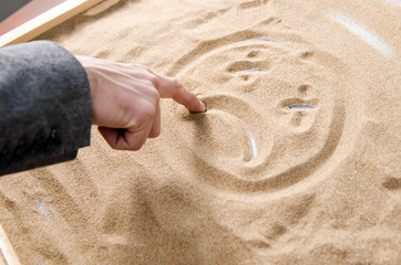 a depressed man drawing by his finger a sad smiley