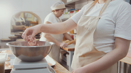 Baker is weighs dough ingredients for baking