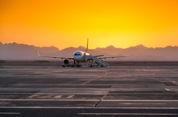 Fototapeta na wymiar Airplane in the Evening Against the Backdrop of the Mountains
