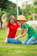 Two school girls exploring the nature with magnifying glass